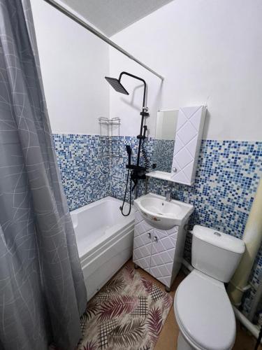 een badkamer met een toilet, een bad en een wastafel bij Apartment on Jeltoksan in Simkent