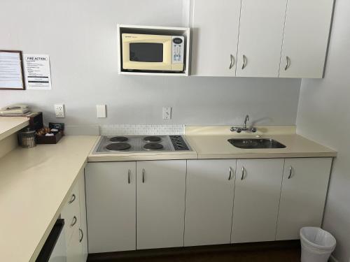 a kitchen with a sink and a microwave at Avenue Motel Palmerston North in Palmerston North