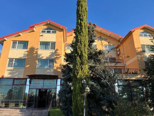 um edifício com uma árvore em frente em Hotel Flora em Drobeta-Turnu Severin
