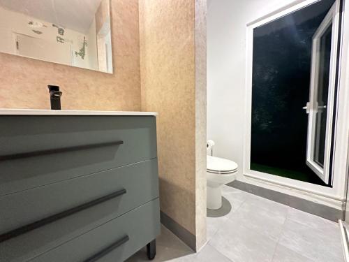 uma casa de banho com um WC, um lavatório e uma janela em Elegante hogar en el centro em Vigo