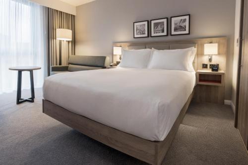 a hotel room with a large bed and a chair at Hilton Garden Inn Manchester Emirates Old Trafford in Manchester