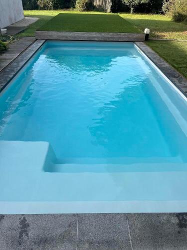 une piscine avec de l'eau bleue dans une cour dans l'établissement Maison de L'Océan - Piscine privé et jardin, à Saint-Pierre-dʼOléron