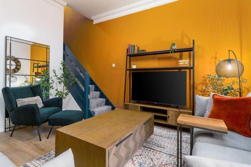 uma sala de estar com uma televisão e um sofá e cadeiras em The Stylish 3-Bedroom Maisonette Retreat em Stirling