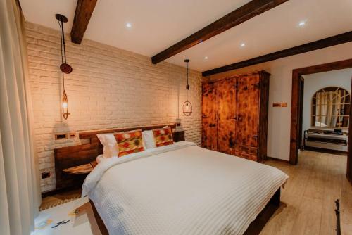 a bedroom with a white bed and a brick wall at The Owl's Nest 2 in Velingrad