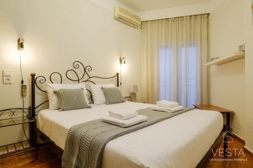 1 dormitorio con 1 cama blanca grande y toallas. en Origami Urban Residence, Vesta Philoxenia, en Tesalónica