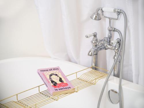 a book sitting on a rack in a bathroom sink at Unique Georgian Garden Flat in Central Margate in Margate