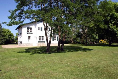 a white house with a tree in a field at grande maison de famille prés d'Hossegor in Bénesse-Maremne