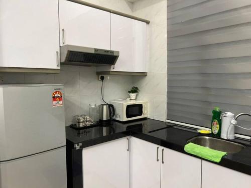a kitchen with a white refrigerator and a microwave at Urban Oasis Retreat in Melaka