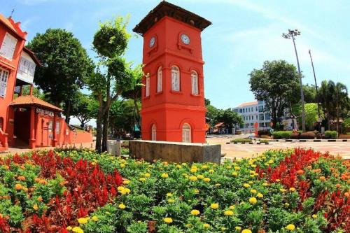 a red clock tower in the middle of a field of flowers at Urban Oasis Retreat in Melaka