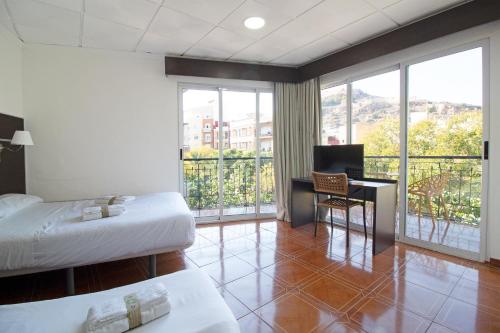 a hotel room with two beds and a desk with a computer at Hotel Sagunto in Sagunto