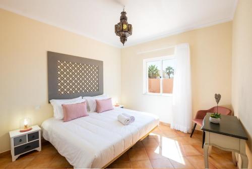 a bedroom with a white bed with pink pillows and a desk at Villa alhabu in Albufeira