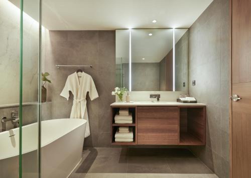 a bathroom with a tub and a sink and a mirror at Bliston Suwan Park View - SHA Plus in Bangkok