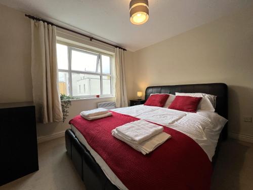 een slaapkamer met een bed met rode kussens en een raam bij Spacious 2BR Flat with Sofa-Bed in Central Reading in Reading