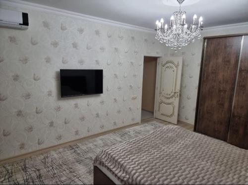 a bedroom with a bed and a tv and a chandelier at Beautiful Villa in Qusar