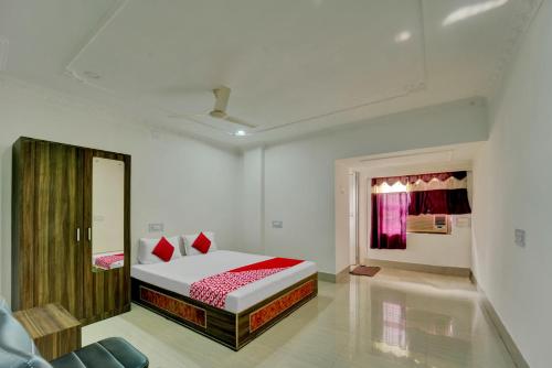 een witte kamer met een bed en een spiegel bij Super OYO Flagship Hotel Shakti Inn in Jamshedpur