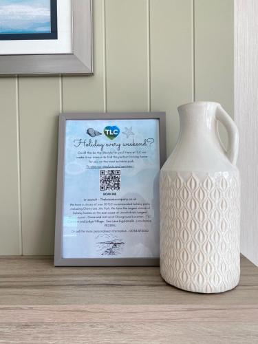 a white vase sitting next to a card and a picture at Bluebell Lodge at The Peaceful Cherry Lea Holiday Park and Fishing Lake Skegness in Skegness