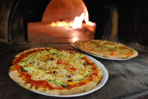 two pizzas sitting on plates in front of an oven at Baia Degli Aranci Suite & Apartments in Vieste