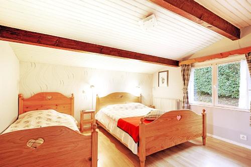 two beds in a room with two windows at Le Chalet Sous les Sapins - Superbe vue in Rochesson