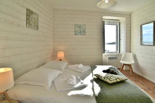 une chambre avec un lit avec des draps blancs et des serviettes dans l'établissement Le Cockpit Cancalais - Bel appt 6 personnes, à Cancale