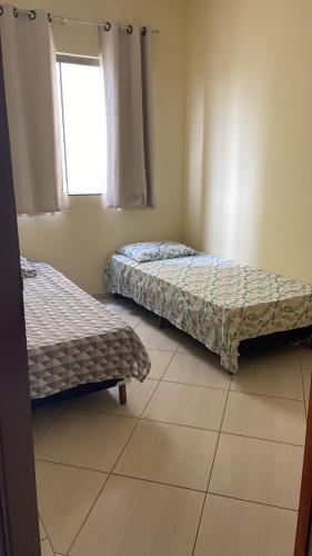 two beds in a room with a window at Apartamento Centro Alfenas in Alfenas