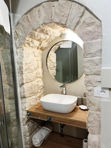 een badkamer met een witte wastafel en een spiegel bij La Casetta b & b in Turi