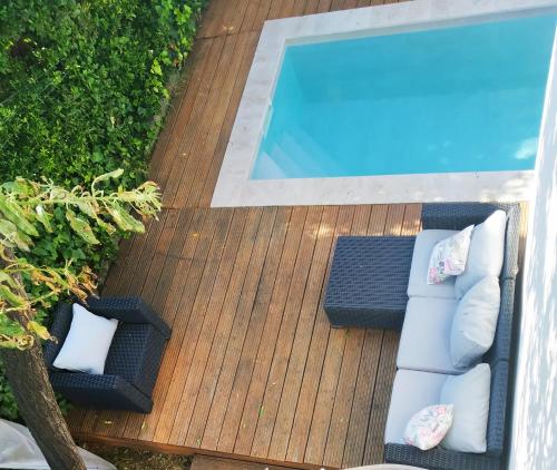eine Terrasse mit 2 Stühlen und einem Pool in der Unterkunft Les lauriers roses & piscine privative in Narbonne