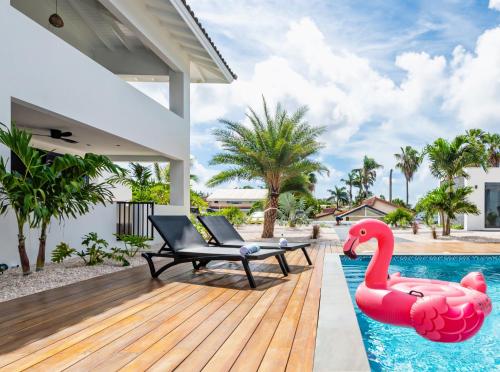 une piscine avec un flamant gonflable rose à côté d'une maison dans l'établissement Palm Suite - Newly constructed poolside apartment just minutes from the beach, à Jan Thiel