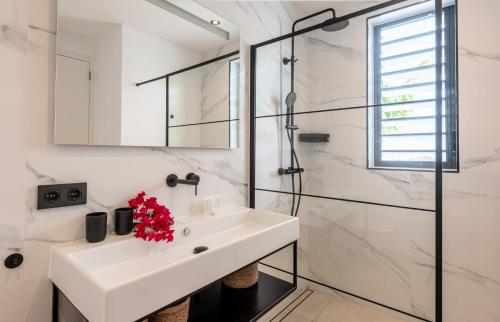 a white bathroom with a sink and a shower at Palm Suite - Newly constructed poolside apartment just minutes from the beach in Jan Thiel