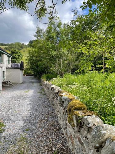 a stone retaining wall next to a road at Stylish Garden Flat Near Loch Ness in Drumnadrochit