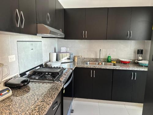 a kitchen with black cabinets and a stove top oven at Apartamento Amueblado en Bonao in Bonao