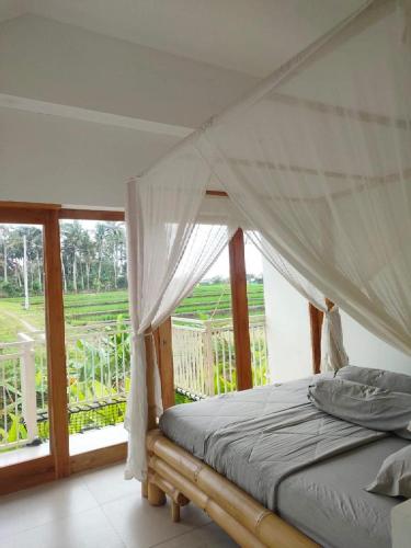 a bedroom with a canopy bed and a large window at Villa Fireflies in Darmasaba