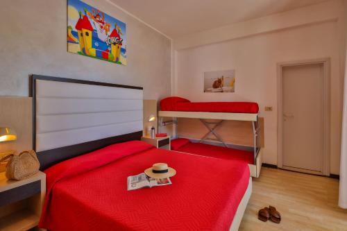 1 dormitorio con 2 literas y manta roja en Ciccio Hotel, en Misano Adriatico