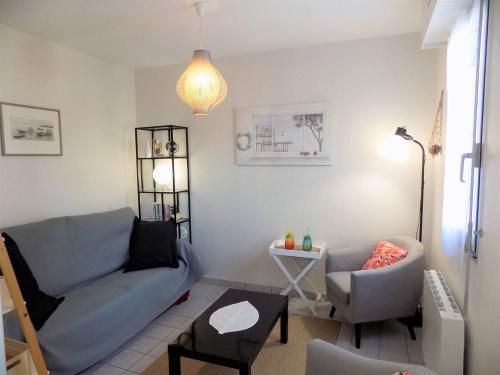 ein Wohnzimmer mit einem Sofa und einem Stuhl in der Unterkunft Saint Georges de Didonne - APPARTEMENT COSY avec BALCON - PROCHE PLAGE in Saint-Georges-de-Didonne