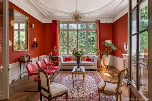 een woonkamer met rode muren en stoelen bij Villa Alecya in Sainte-Catherine-de-Fierbois