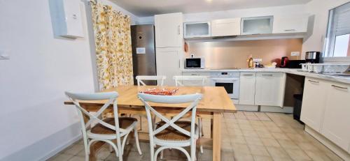 a kitchen with a wooden table and white cabinets at Gîtes de l'AKWABA in Buzet-sur-Baïse