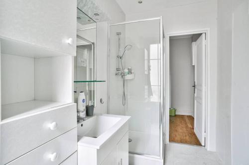 ein weißes Bad mit einem Waschbecken und einer Dusche in der Unterkunft Charmant T2 à 5 minute de Paris in Issy-les-Moulineaux