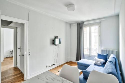 ein Wohnzimmer mit einem blauen Sofa und weißen Stühlen in der Unterkunft Charmant T2 à 5 minute de Paris in Issy-les-Moulineaux