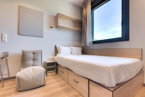 1 dormitorio con cama, ventana y silla en Livensa Living Studios Bilbao en Bilbao