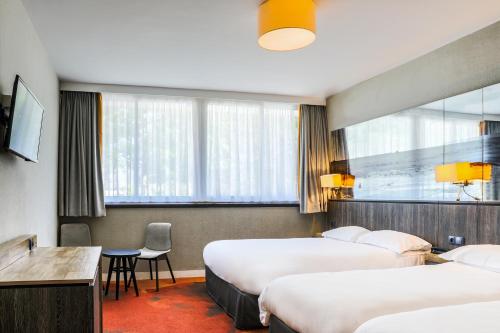モンサンミッシェルにあるホテル ドゥ ラ ディーグのベッド3台、テーブル、椅子が備わるホテルルームです。