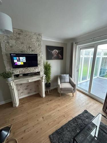 a living room with a tv on a stone wall at Modern & Comfortable with Free Parking in Bedford