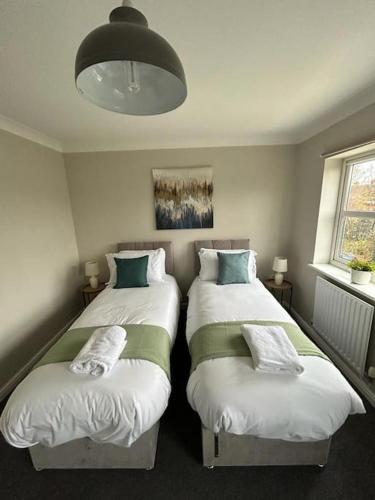 a bedroom with two beds and a chandelier at Modern & Comfortable with Free Parking in Bedford