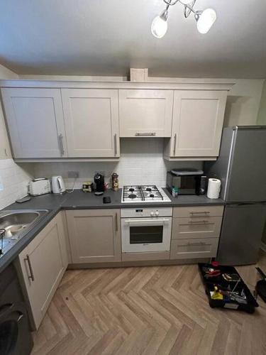 a kitchen with white cabinets and a stove top oven at Modern & Comfortable with Free Parking in Bedford