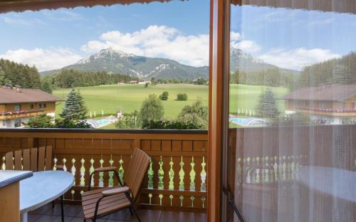 a balcony with a table and chairs and a large window at Landhotel Häuserl im Wald in Gröbming