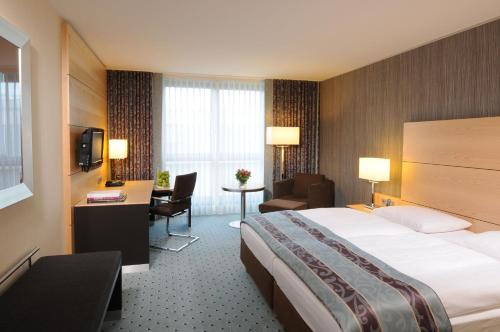 ein Hotelzimmer mit einem großen Bett und einem Schreibtisch in der Unterkunft Maritim Hotel Düsseldorf in Düsseldorf