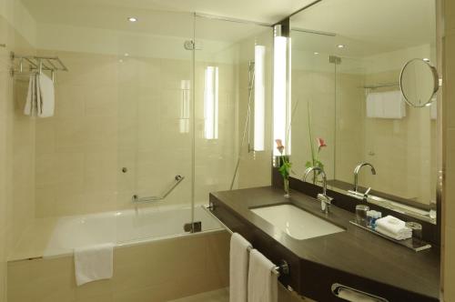 ein Badezimmer mit einer Badewanne, einem Waschbecken und einem Spiegel in der Unterkunft Maritim Hotel Düsseldorf in Düsseldorf