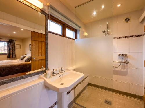 a bathroom with a sink and a shower and a bed at The Hayloft in Canterbury