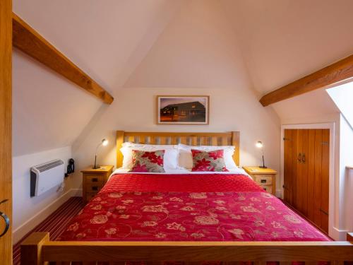 a bedroom with a bed with a red bedspread at The Hayloft in Canterbury