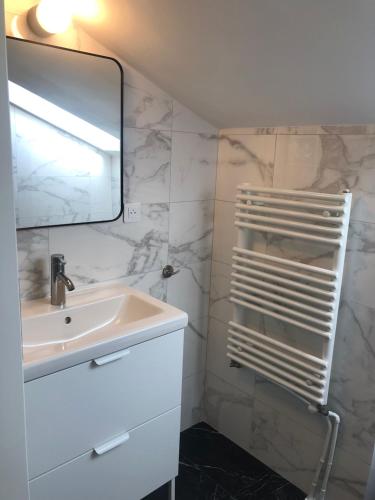 uma casa de banho branca com um lavatório e um espelho em AparisAppart em Pantin