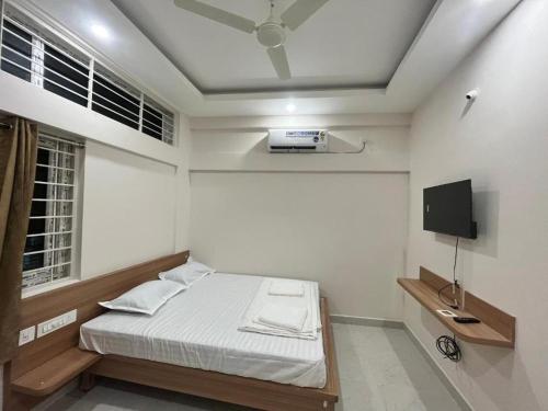 a small bedroom with a bed and a tv at Seema Palace Inn in Mysore