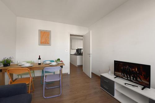 een woonkamer met een eettafel en een televisie bij Santi Apartment Few Min From Lake - Happy Rentals in Lugano